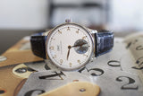 Luxury pre-owned IWC Portuguese hand-wound watch with black leather strap and white dial