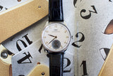 IWC Portuguese hand-wound luxury watch with black leather strap on artistic background