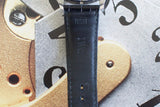 Close-up of black leather watch strap with IWC engraving against mechanical watch dial background