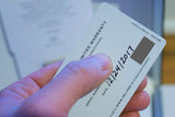 Hand holding IWC limited warranty card with handwritten date, close-up