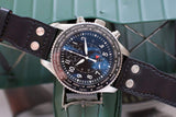 Black dial chronograph watch with city names bezel, black leather strap, close-up shot