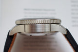 Side profile of stainless steel luxury watch case with black leather strap