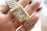 Close-up of a Jaeger-LeCoultre Reverso luxury watch with a gold and steel bracelet on a wrist.