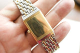 Close-up of a two-tone gold and silver luxury watch bracelet and clasp held in a hand.