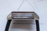 Side view of a rectangular stainless steel luxury watch case with black leather strap