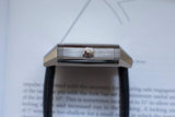 Side view of a luxury rectangular watch with leather strap on a white background