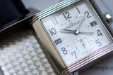 Close-up of luxury Swiss-made rectangular watch with silver case and day display