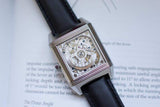 Rectangular luxury Swiss watch with visible mechanical movement and black leather strap