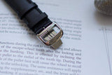 Black leather luxury watch strap with stainless steel clasp on open book