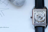 Luxury Swiss watch with visible mechanical movement and black leather strap on white background