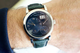 Luxury Swiss watch with black dial, Roman numerals, date window, and green leather strap on wrist