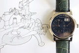 Luxury A. Lange & Söhne watch with black dial and green leather strap on technical drawing background