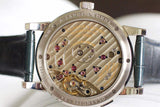 Luxury watch caseback with visible mechanical movement and engraved detailing.