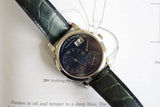 Luxury A. Lange & Söhne wristwatch with black dial and leather strap on an open book