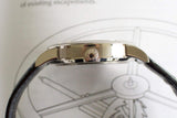 Side view of a luxury watch with metal case, engraved crown, and black leather strap
