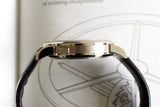 Side profile of a luxury wristwatch with a leather strap, silver case, on a technical drawing background