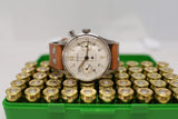 Lemania chronograph luxury watch with leather strap displayed on box of brass cartridges