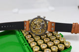 Open caseback Swiss chronograph watch with brown leather strap on brass ammunition cartridges