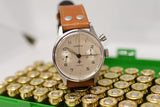 Lemania mono-pusher chronograph watch with tan leather strap on ammunition rounds