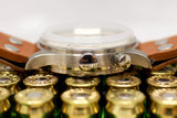 Side view of a vintage chronograph watch with a domed crystal and leather strap on brass casings