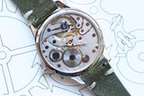Close-up of Minerva 140th Anniversary limited edition men's watch with visible mechanical movement and green suede strap.