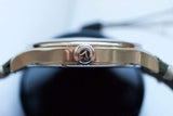 Gold men’s luxury watch side profile close-up showing engraved crown and brushed case