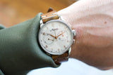 Close-up of a vintage Minera chronograph watch with a brown leather strap on a wrist.