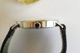 Close-up side view of stainless steel luxury watch case with black leather strap