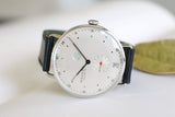 Minimalist luxury watch with white dial, subdials, date window, and black leather strap
