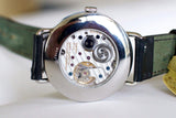 Close-up of luxury watch movement with visible gears and leather strap on display