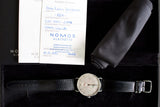 Nomos Metro Gangreserve luxury wristwatch with black leather strap, warranty card, box, and cloth
