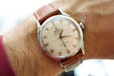 Vintage Omega Constellation automatic watch with silver dial and brown leather strap on wrist