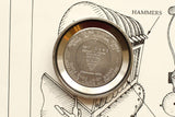 Close-up of a stainless steel Omega watch case back resting on a technical drawing.