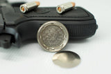 Omega watch case back with Swiss-made engraving, placed near handgun grip and two bullets.