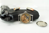 Open vintage mechanical watch movement near handgun and bullets on white background