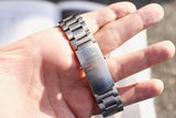 Close-up of an Omega Seamaster Professional stainless steel watch bracelet clasp in a hand.