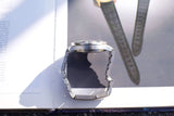 Rear view of a luxury stainless steel watch with a metal bracelet on a book page