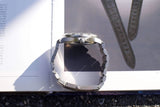 Close-up side view of a luxury stainless steel watch on a white background