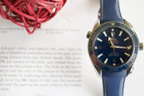 Omega Seamaster luxury dive watch with blue dial and strap on a book background