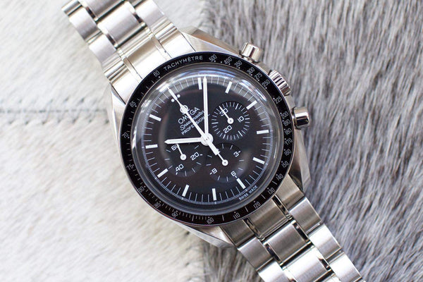 Stainless steel chronograph watch with black dial and tachymeter bezel on a fur background