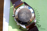 Case back of an Omega Speedmaster luxury watch with a brown leather strap