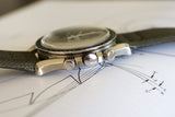 Side view of vintage Swiss chronograph watch with green strap and steel case on technical drawing