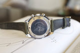 Vintage Omega Speedmaster watch back with engraved logo and black strap on open book