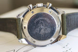 Close-up of vintage Omega Speedmaster watch caseback with engraved logo and leather strap