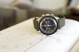 Vintage Omega Speedmaster chronograph with black dial and green strap on technical drawing