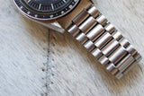 Close-up of stainless steel luxury watch bracelet and black dial chronograph on textured surface