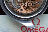 Close-up of Swiss watch movement with exposed gears and Omega logo in background