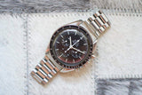 Stainless steel Omega Speedmaster Professional chronograph watch with black dial on light textured background