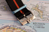 Detailed close-up of a black and orange striped luxury watch strap with a metal clasp on a map.