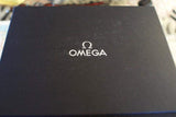 Black Omega watch box with white logo on top, luxury timepiece packaging